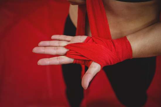 Mid section of female boxer wearing red strap on wrist in fitness studio